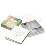 Printed cards featuring multiple stacks of inspirational cards with abstract angel artwork, including one with vibrant pink and teal hues and another with muted purple, alongside visible scripture from 1 John 4:9-11 with a small red heart icon