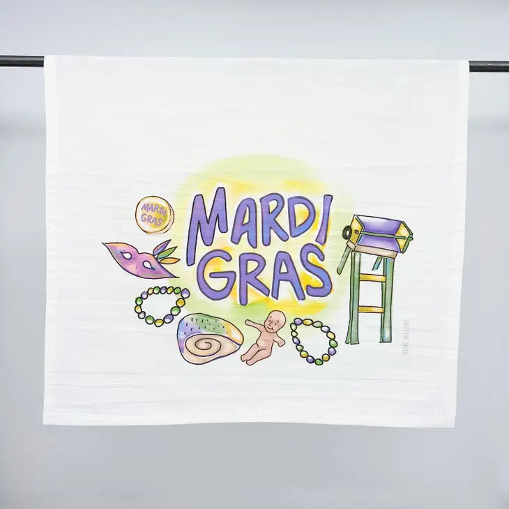 Watercolor illustration by Kate Wilcox on a white towel depicting New Orleans Mardi Gras with vibrant purple lettering, a masquerade mask, green and gold beads, a king cake slice with a baby, and a parade ladder stand