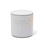 White ceramic candle jar with lid featuring an embossed dragonfly design and an orange Palo Santo Citronella label