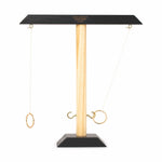 Digital photo by Gentlemen's Hardware showing a wooden ring toss game with a light natural wood central pole, matte black top and base, two brass rings on white strings, and one ring successfully hooked onto a brass hook