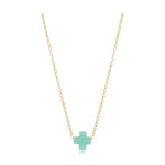 Jewelry product photo of a delicate gold chain necklace featuring a small minimalist pastel green cross pendant with a subtle reflection underneath on a stark white background