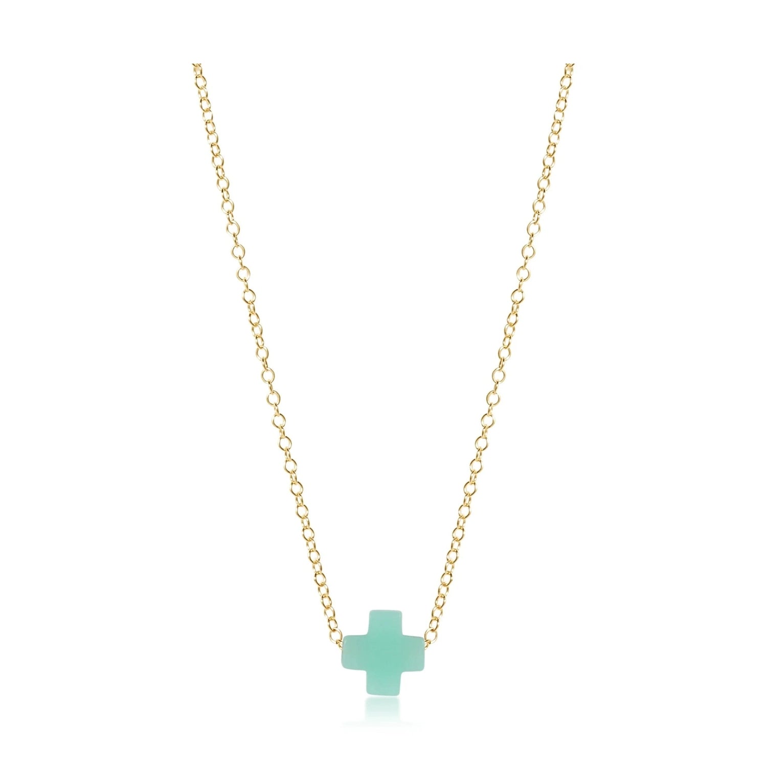 Jewelry product photo of a delicate gold chain necklace featuring a small minimalist pastel green cross pendant with a subtle reflection underneath on a stark white background