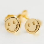 Petite gold stud earrings with an embossed happy face design gleaming in yellow gold
