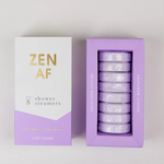 CHEZ GAGNÉ white and lavender "ZEN AF" shower steamers box with gold lettering alongside its open packaging showing eight round lavender + rosemary steamers and inner "HEAVILY MEDITATED" text