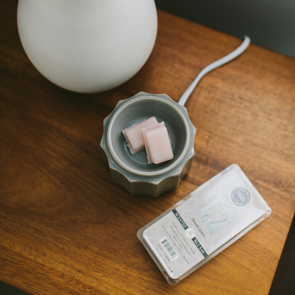 An overhead shot of the sweet grace scented wax bars in a wax warmer on a wooden tabletop