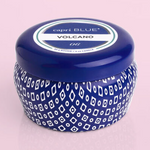 blue candle tin labeled capri blue volcano scent on a light pink background