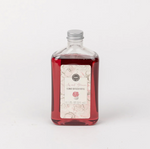 A clear glass bottle with a label that reads 'Sweet Grace Flower Diffuser Oil', containing red-colored oil.