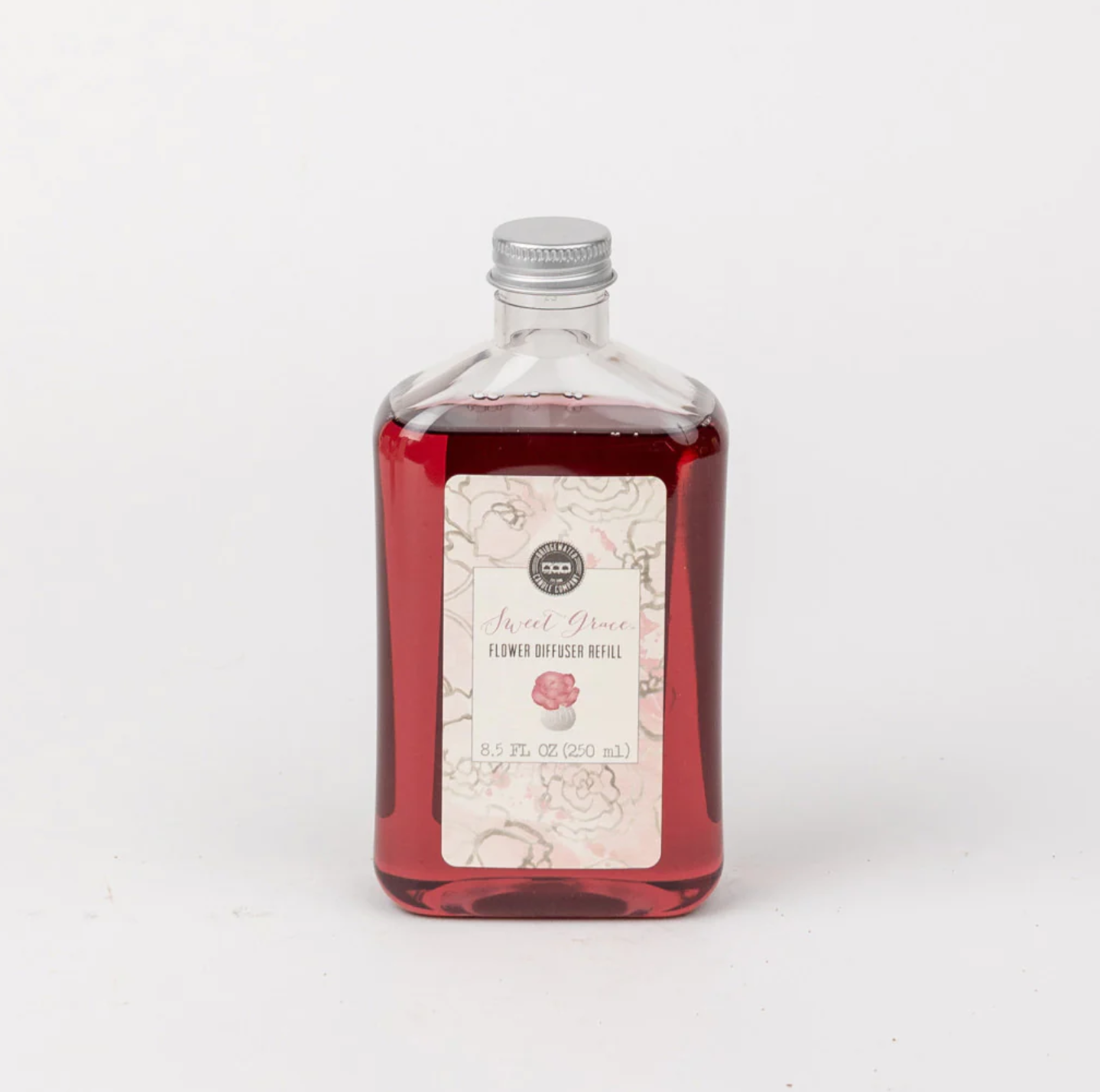 A clear glass bottle with a label that reads 'Sweet Grace Flower Diffuser Oil', containing red-colored oil.