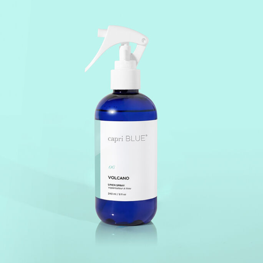 blue and white linen spray bottle labeled capri blue volcano on a light blue background