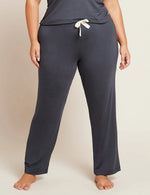 A person standing wearing grey 
sleep pants with a drawstring and a wide leg design.